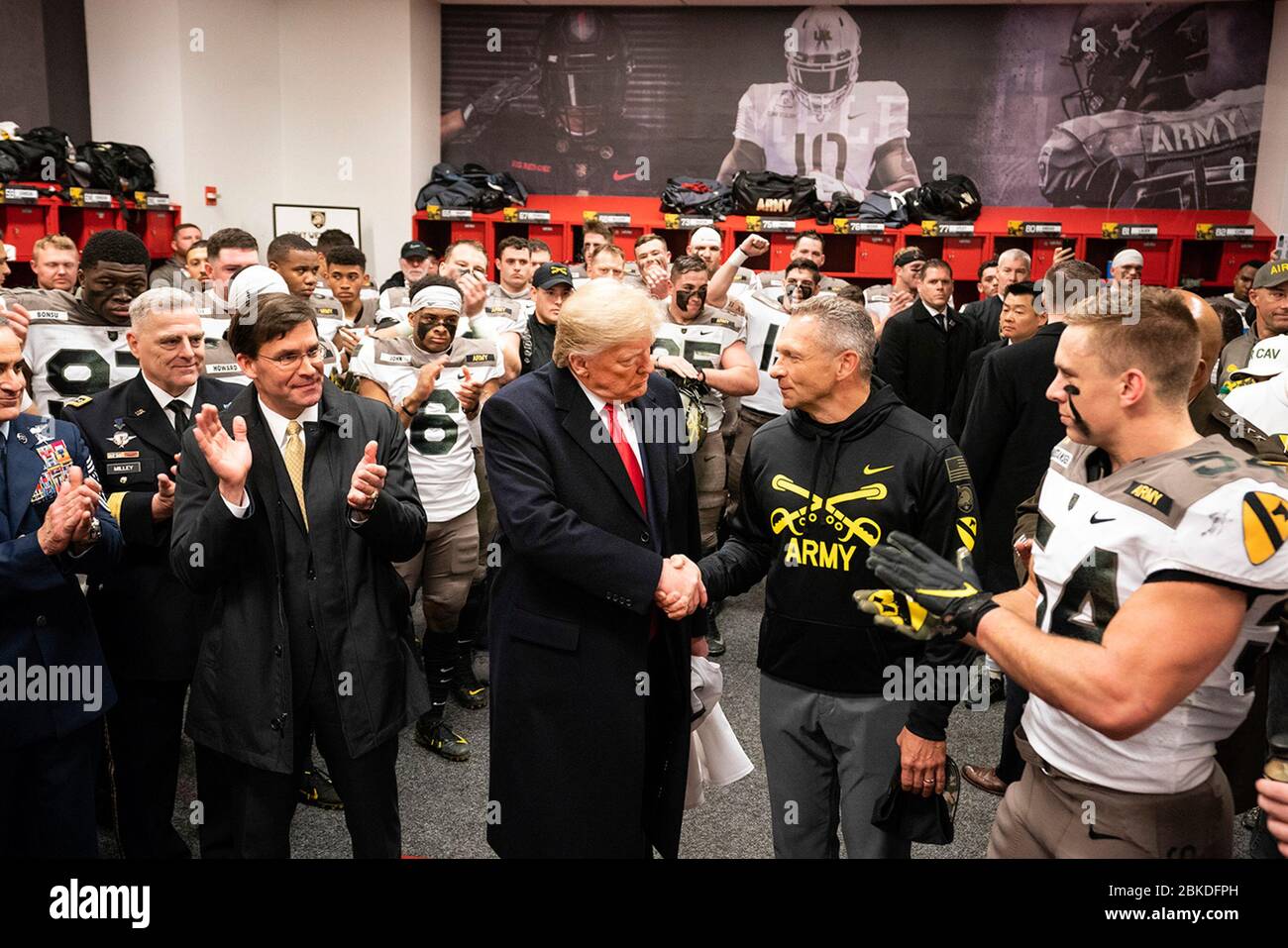 President Donald J. Trump, joined by Secretary of Defense Mark Esper, shakes hnads with coach Jeff Monken as he meets with members of the U.S. Army football team in their locker room prior to the start of the 120th Army-Navy football game at Lincoln Financial Field in Philadelphia, Pa. President Trump at the Army-Navy Football Game Stock Photo