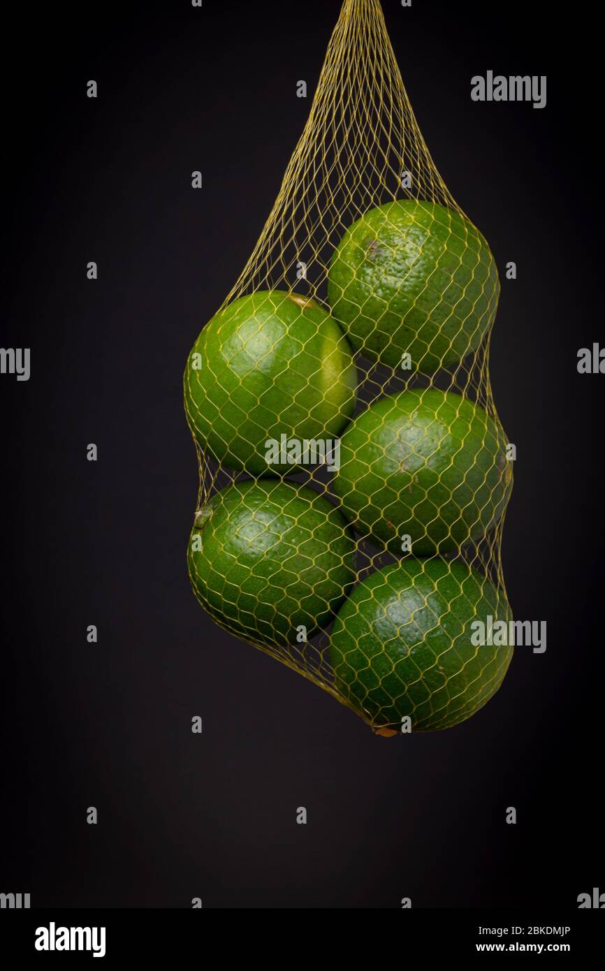 Hanging yellow gauze netting bag with a couple of fresh vibrant green