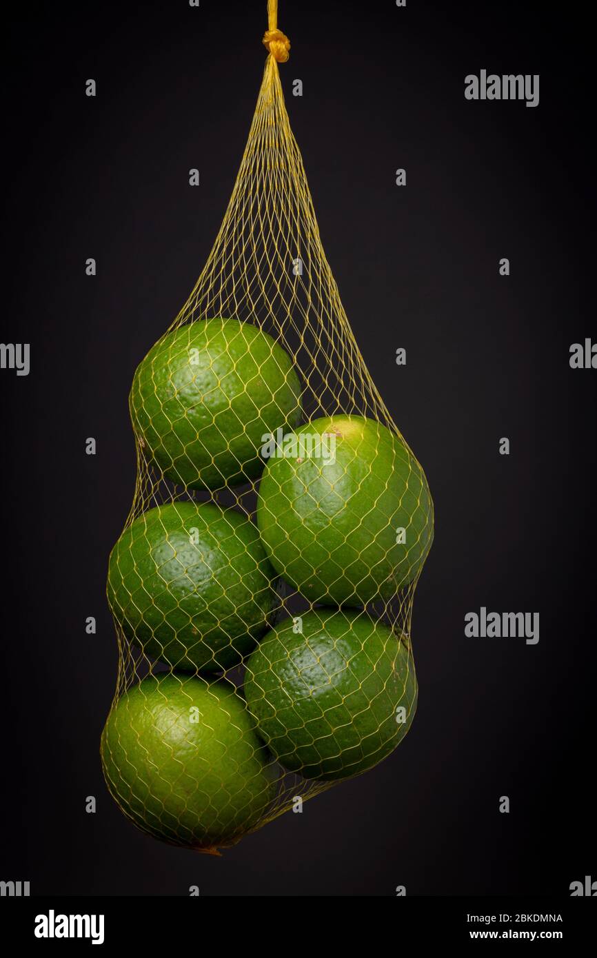 Yellow gauze netting bag with a lot of fresh vibrant green lime fruit