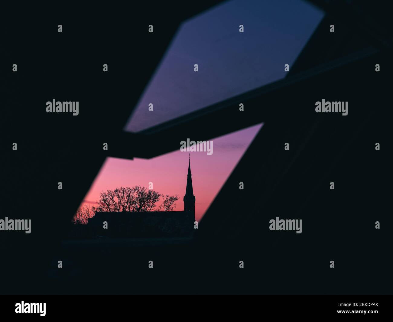 Close up view through open roof window. Cathedral and tree on sunset sky background. The Hague, Netherlands Stock Photo