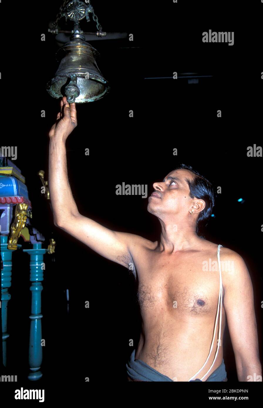 Young Brahmin priest rings temple bell for worship Stock Photo
