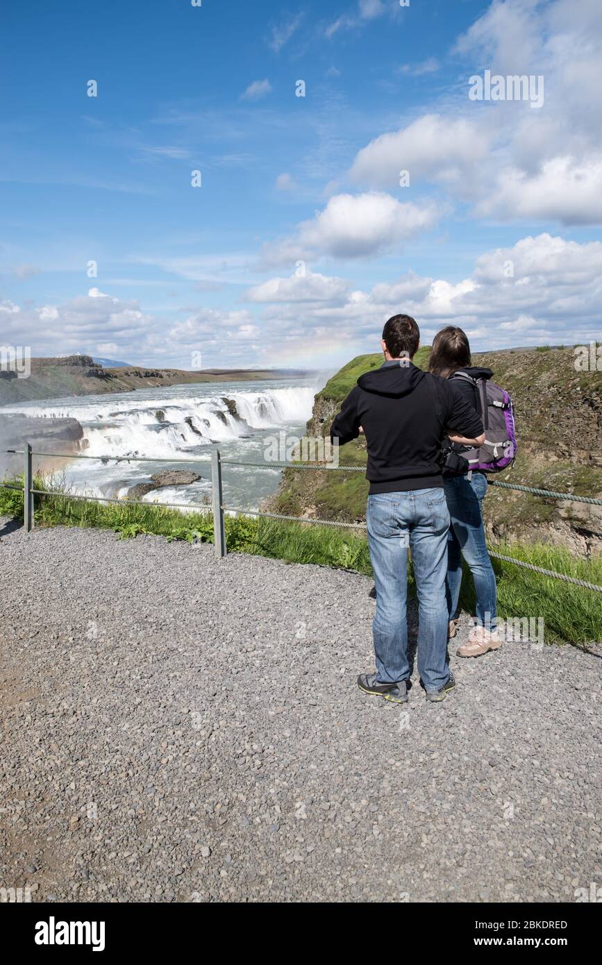 Young couple looking out at the beautiful waterfall in Iceland while on vacation. Stock Photo