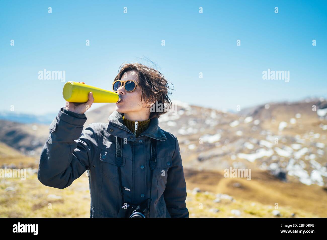 Young woman spending free time in national park/mountains.Hiking outdoor experience.Drinking from reusable vacuum insulated water bottle.Environmental Stock Photo