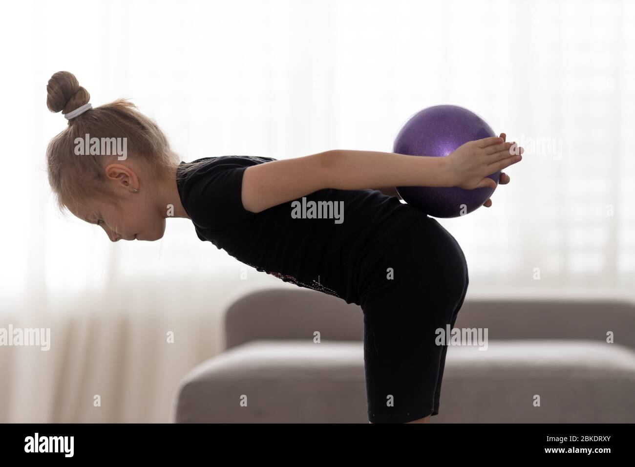 Flexible cute little girl child gymnast doing acrobatic exercise with ball. Sport, training, fitness, active lifestyle concept Stock Photo