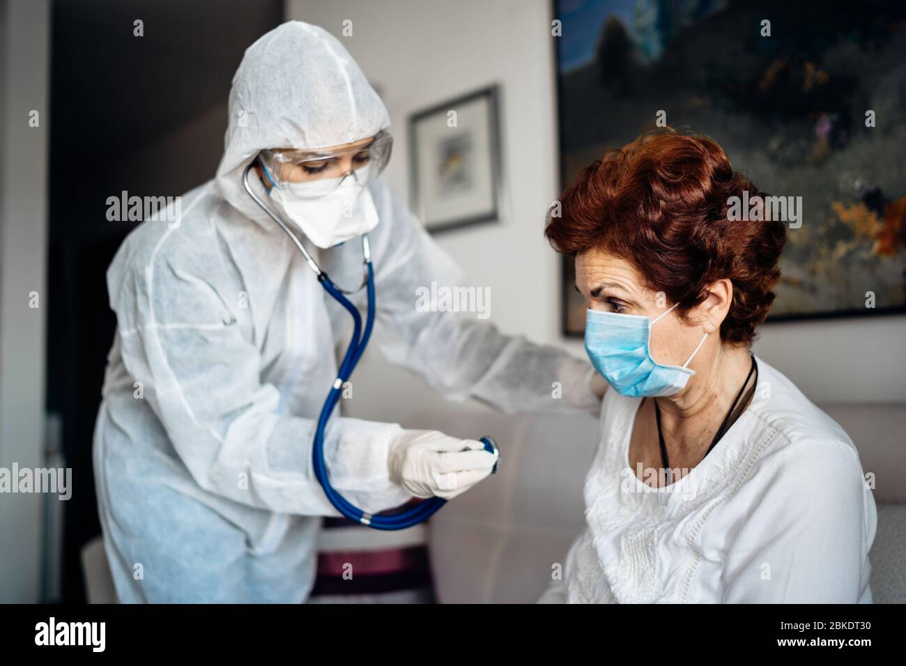 Home care doctor/nurse listening to the senior patients’ lungs with a stethoscope.COVID-19 patient self isolation examination.Coronavirus frontline me Stock Photo