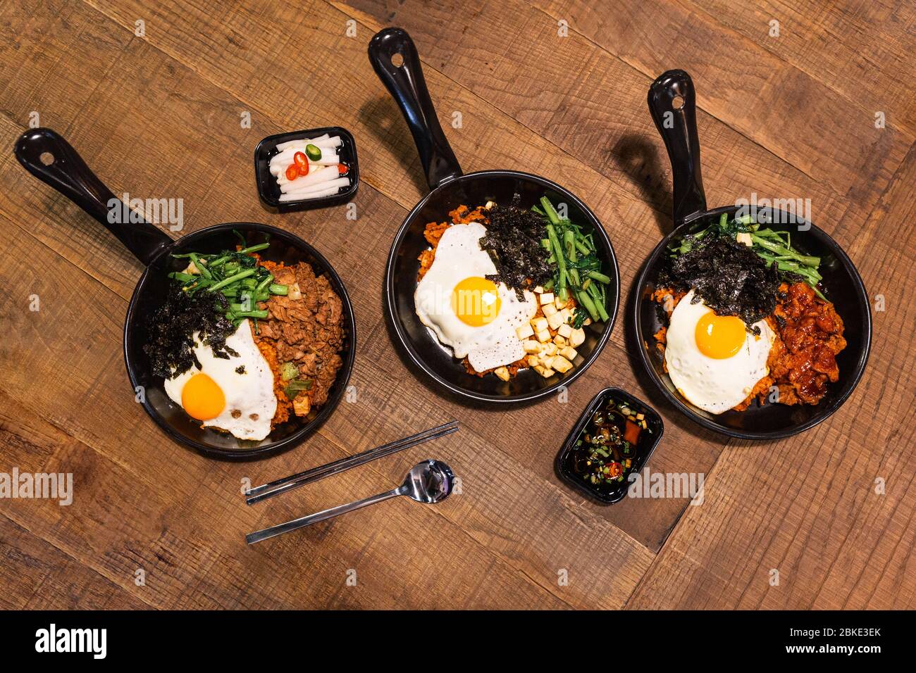 Flatlay of Bibimbap (Korean rice mixed with kimchi pork, tofu, seaweed and stir fried vegetables topping with sesame) served on the hot pan. Stock Photo