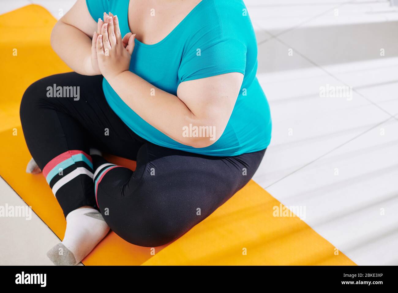 Plus size woman meditating on yoga mat at home and keeping hands in namaste  gesture Stock Photo - Alamy
