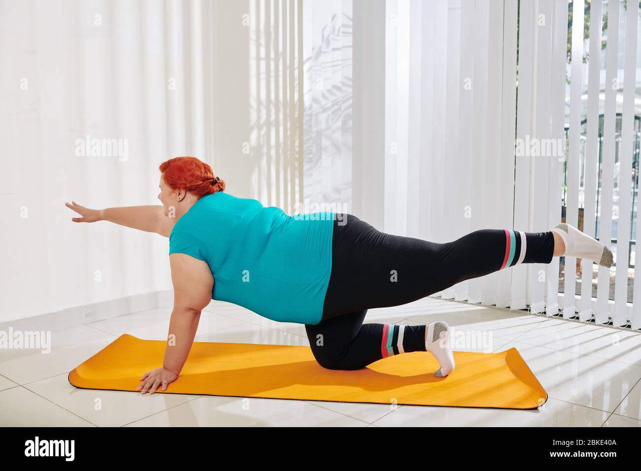 Young plus size woman doing table top exercise on yoga mat at mat