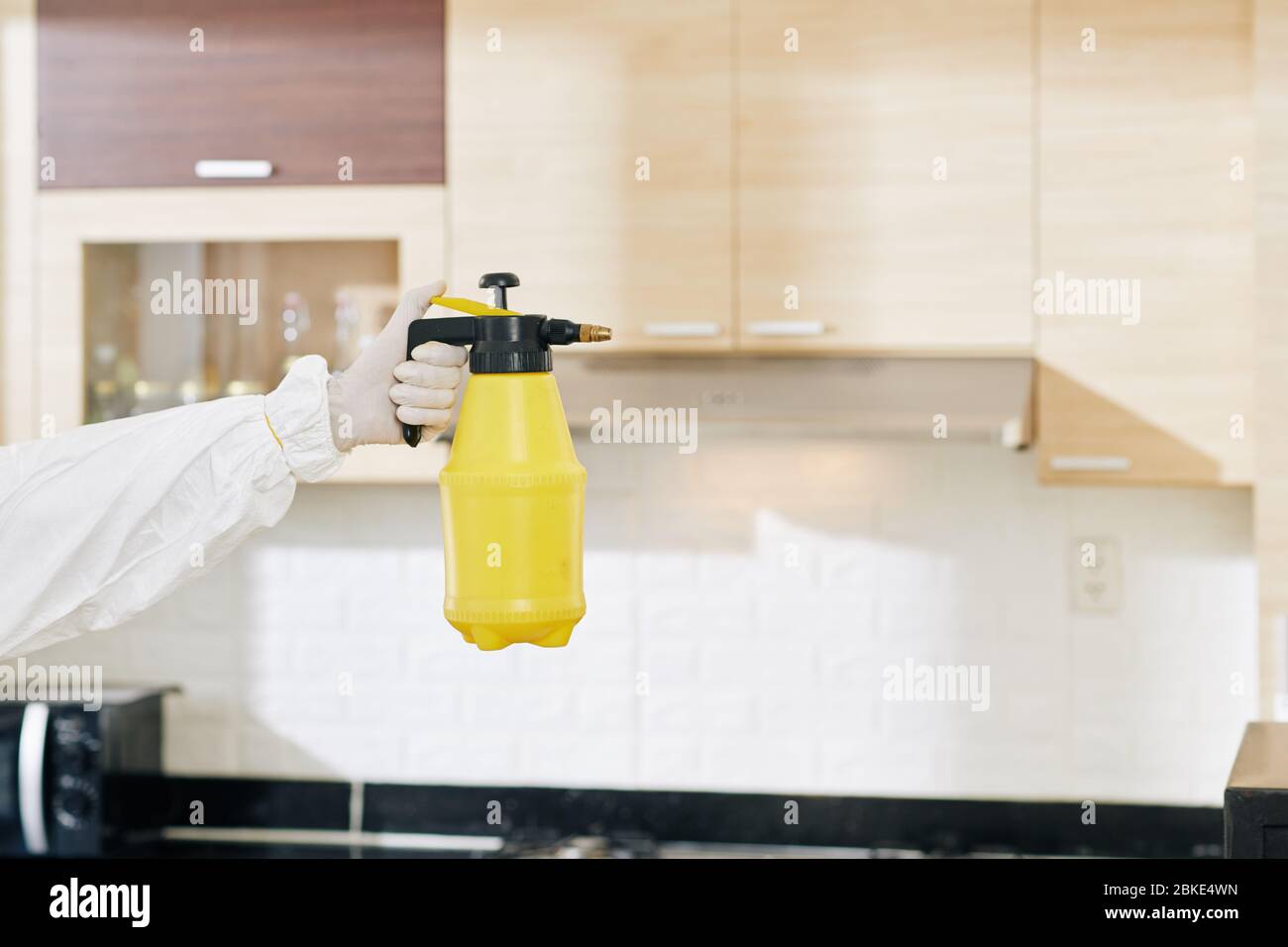 Gloved hand of technician holding bottle of detergent that help to get
