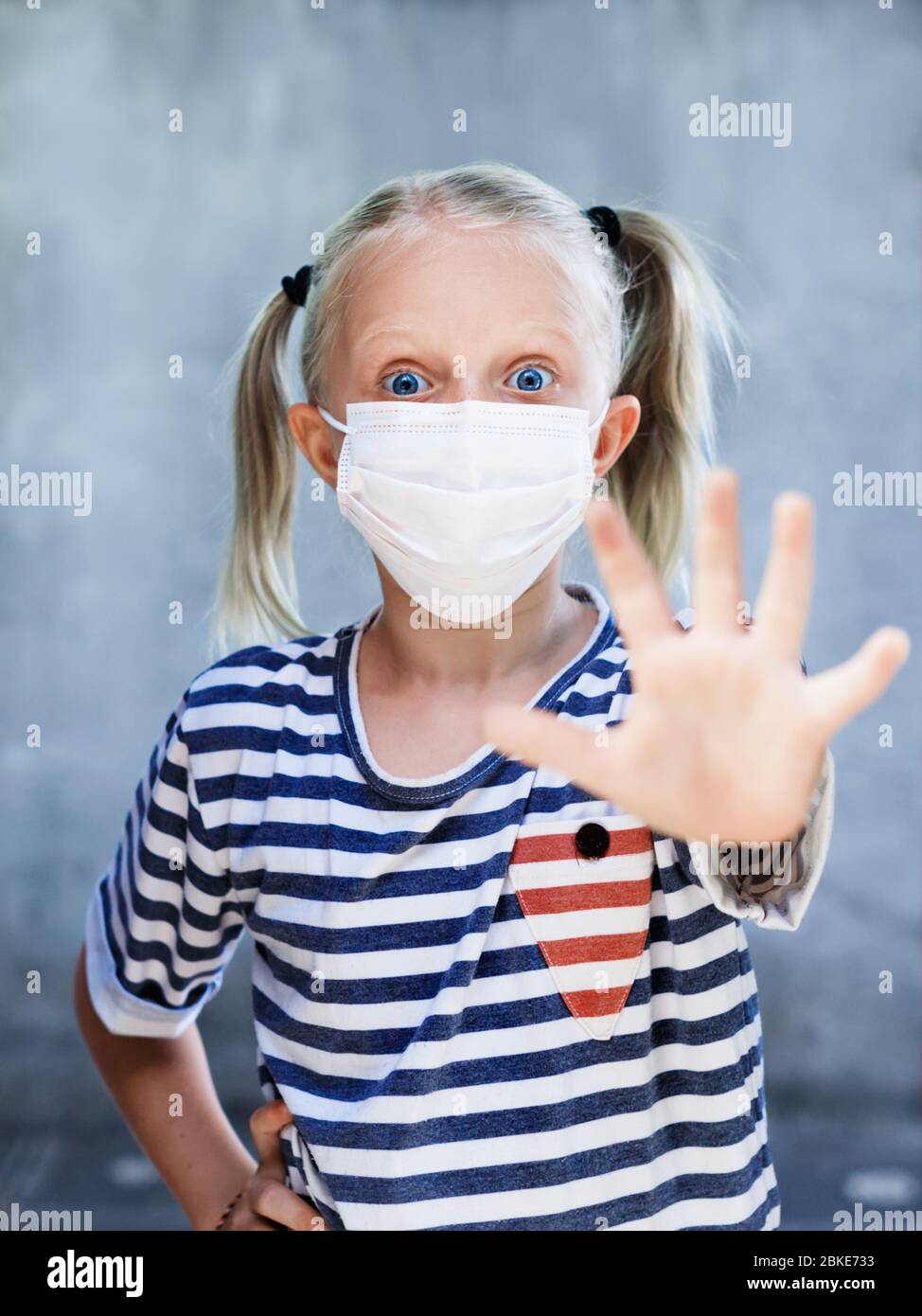 Little child showing hand gesture Stop virus. Kid wearing medical face masks go out for outside walk after staying at home due banned street activity. Stock Photo
