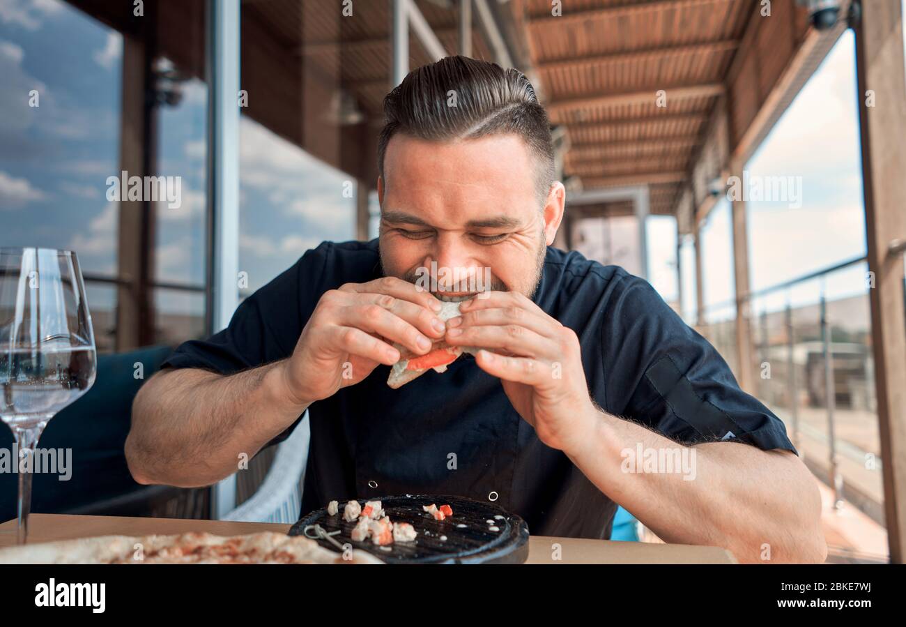 the bearded man takes a bite of his sandwich Stock Photo