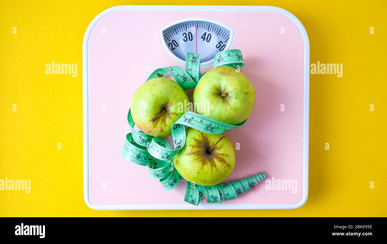 Green Apple with measuring tape and pink Weight scales. Concept of