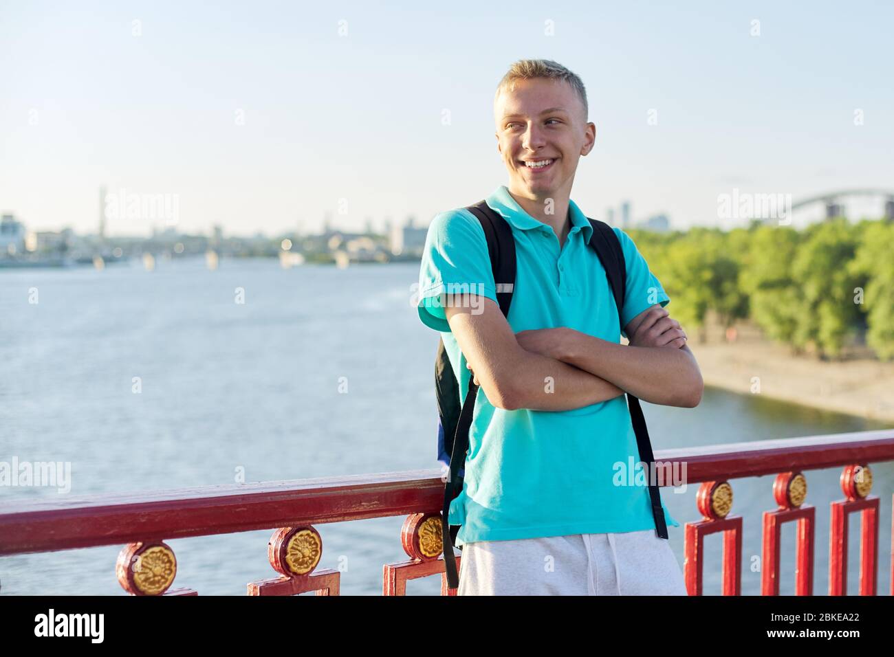 Outdoor portrait of smiling teenage boy 15, 16 years old with arms