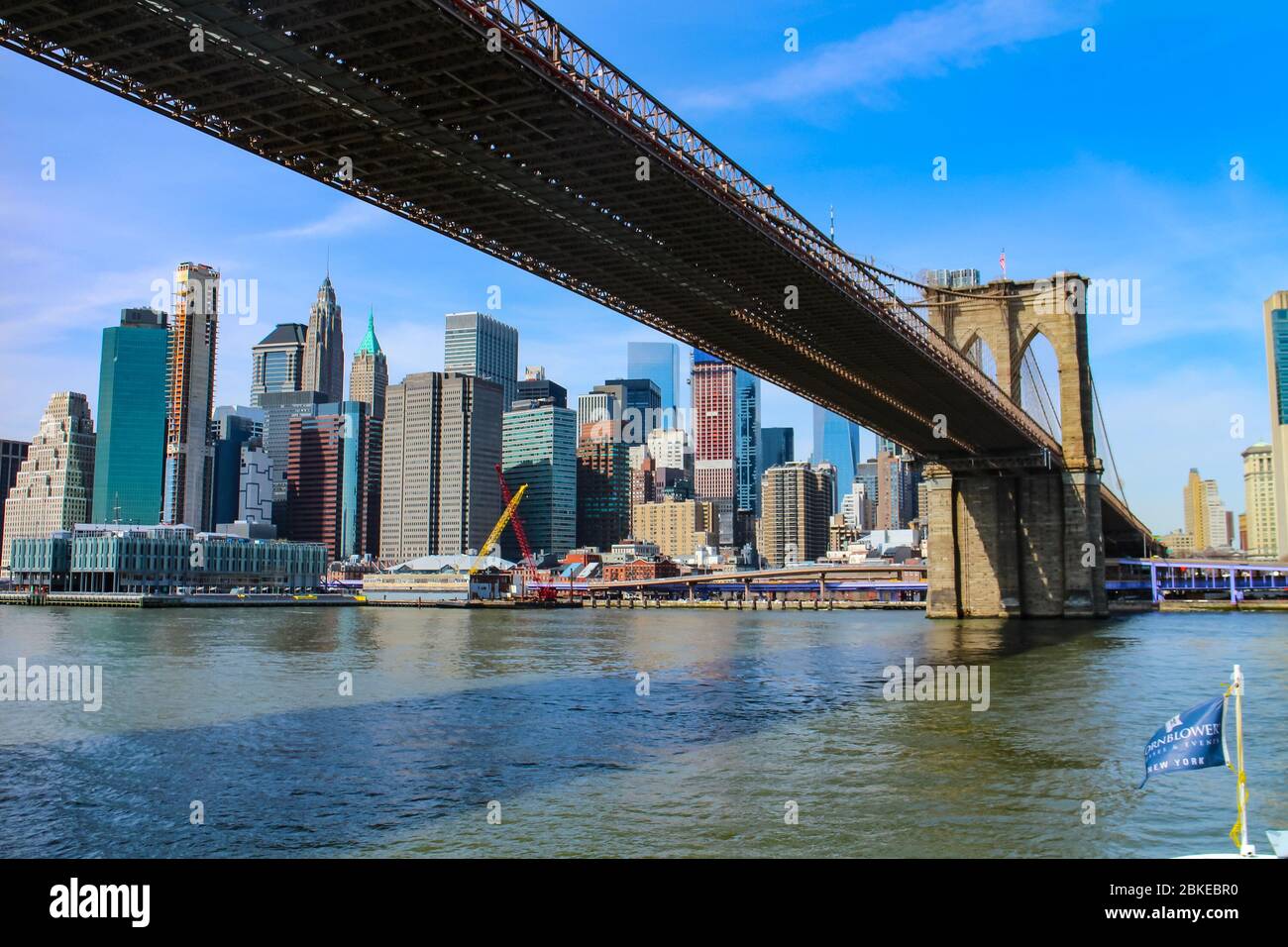Iconic view from Brooklyn under the Brooklyn Bridge towards the skyline of Lower Manhattan. Stock Photo
