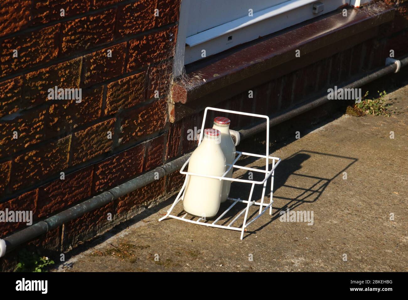 Milk crate on driveway by front door of a house with doorstep milk