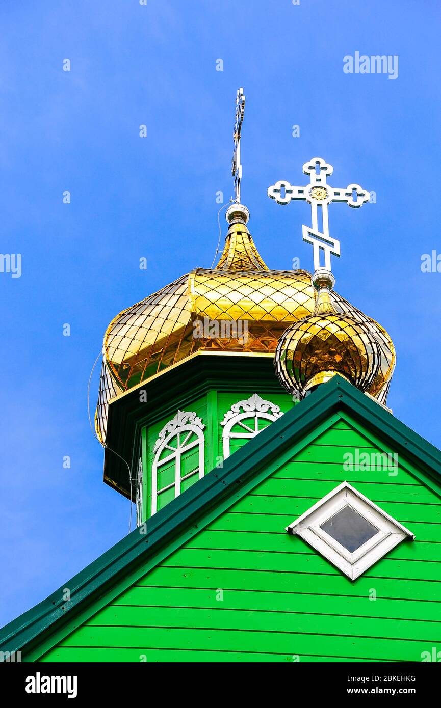 Onion dome and bell tower of the Saint Michael Archangel, Eastern Orthodox Church in Trzescianka, Poland. Golden domes, green tower clear blue sky bac Stock Photo