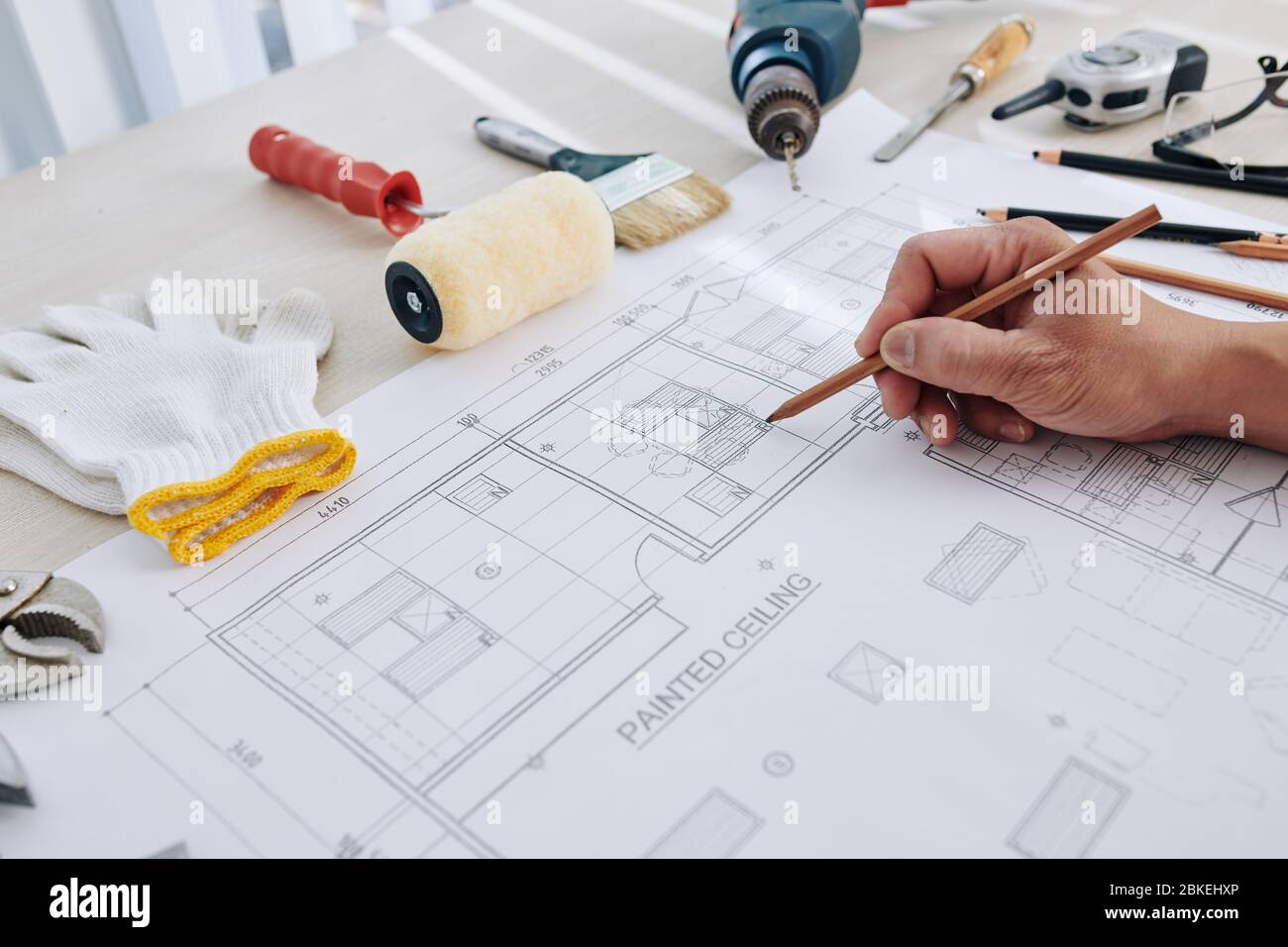 Construction engineer making final corrections in building blueprint or checking size of every detail Stock Photo