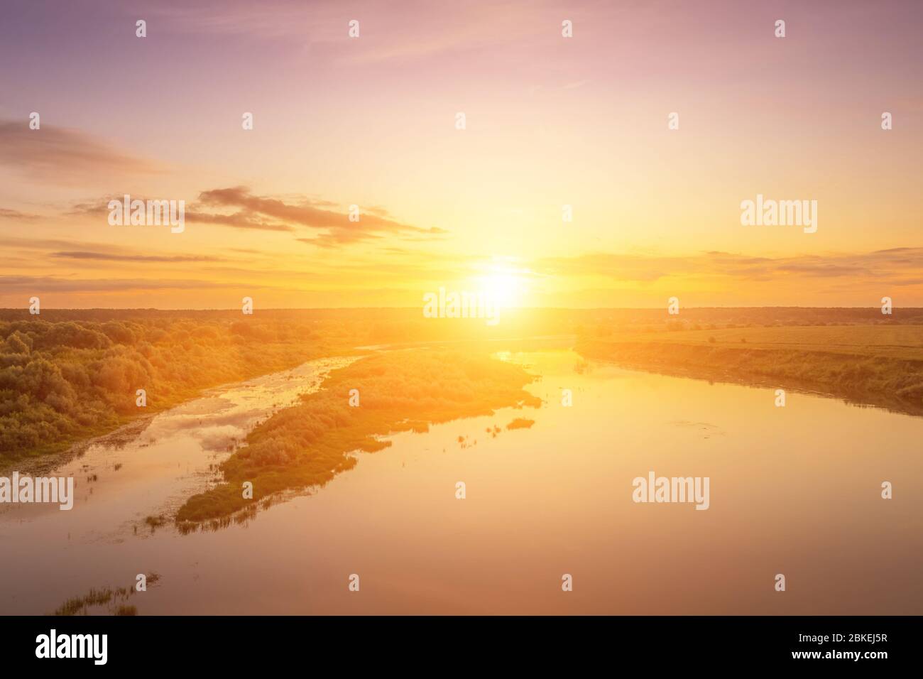 Aerial view to sunset on the river at summer evening with clouds and trees. Water reflection of a sky. Stock Photo