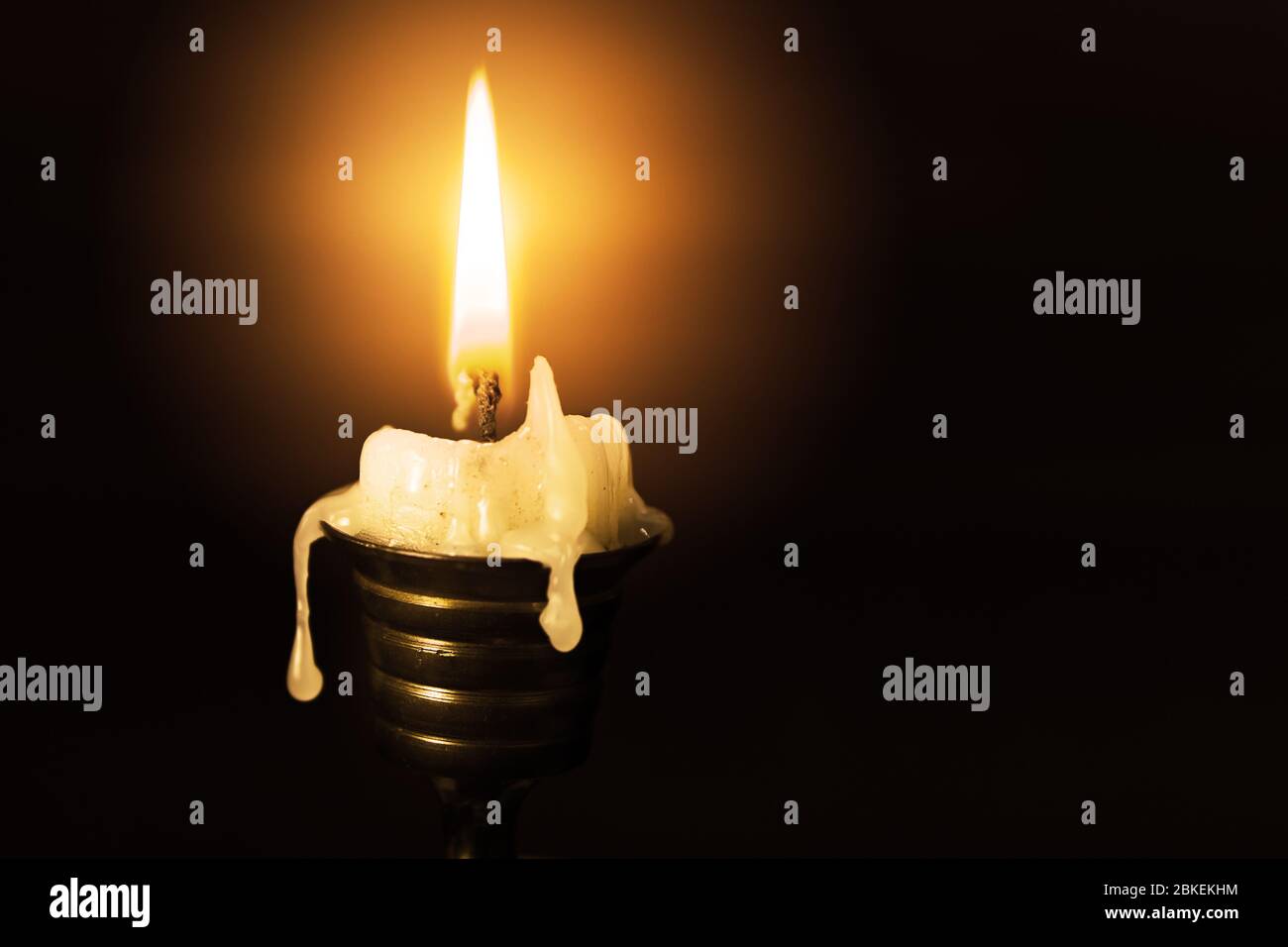 Light candle in the brass candlestick closeup on a dark background with a text space Stock Photo