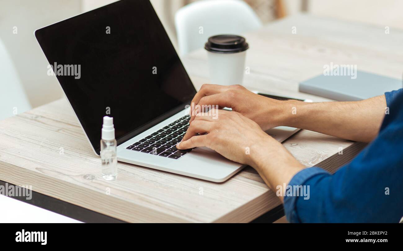young man working on a laptop, observing security measures Stock Photo