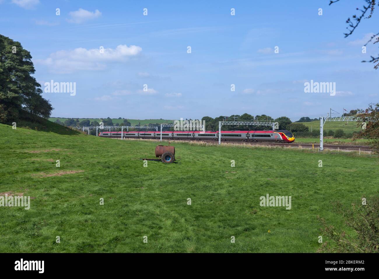 Virgin trains class 390 Alstom Pendolino passing through the countryside at Stableford, Staffordshire on the 4 track west coast mainline Stock Photo