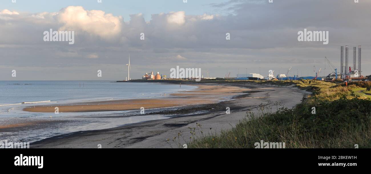 The beach at Cambois Northumberland looking back to an oil rig in the harbour at Blyth Stock Photo