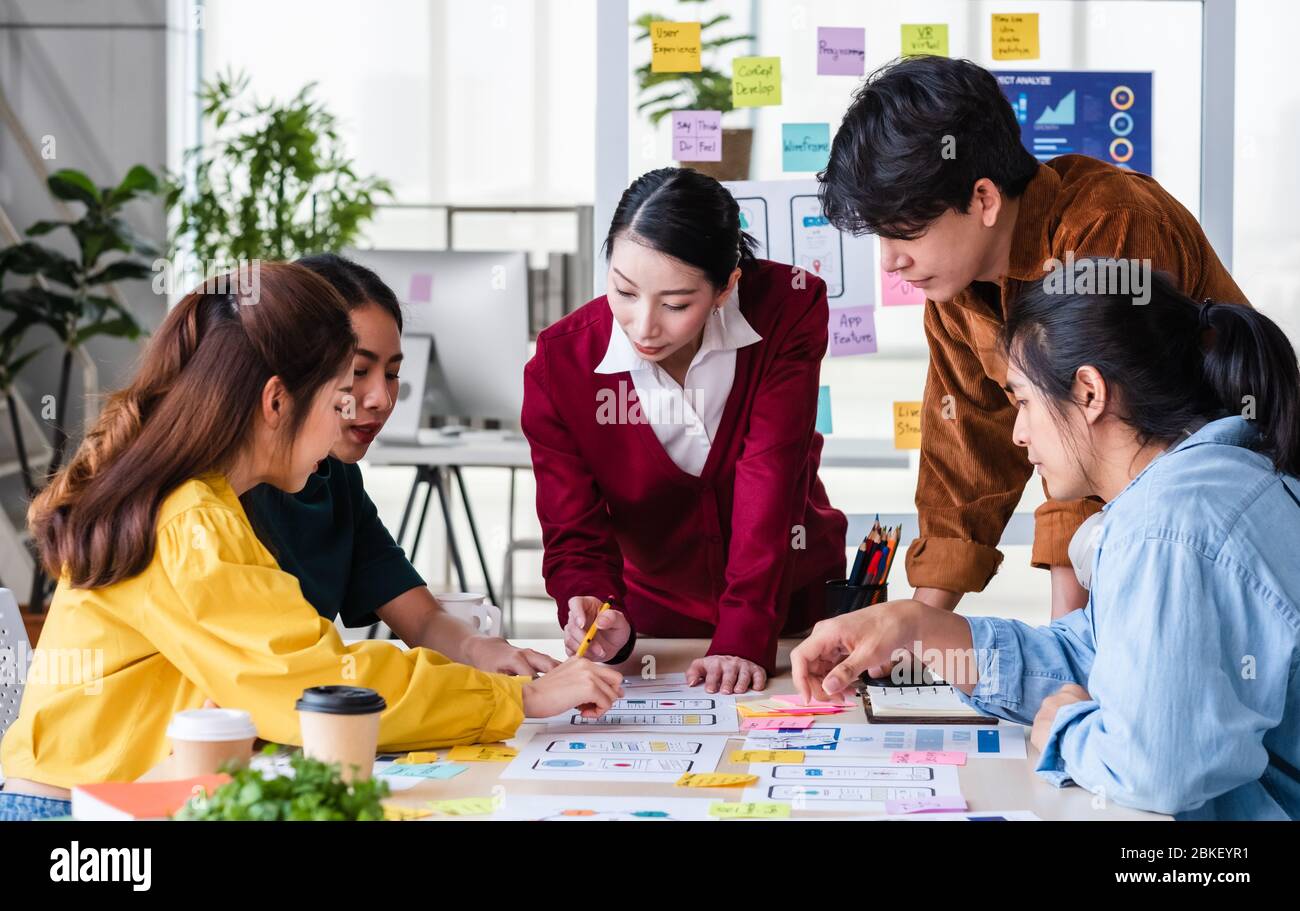 ux developer and ui designer brainstorming about mobile app interface wireframe design on meeting table with customer brief and color code at modern o Stock Photo