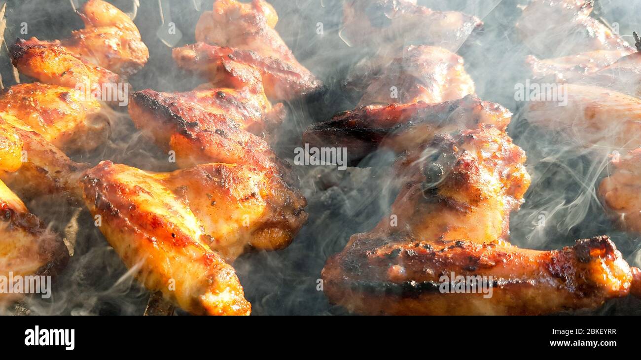 Delicious juicy grilled chicken wings outdoors in smoke. BBQ Chicken