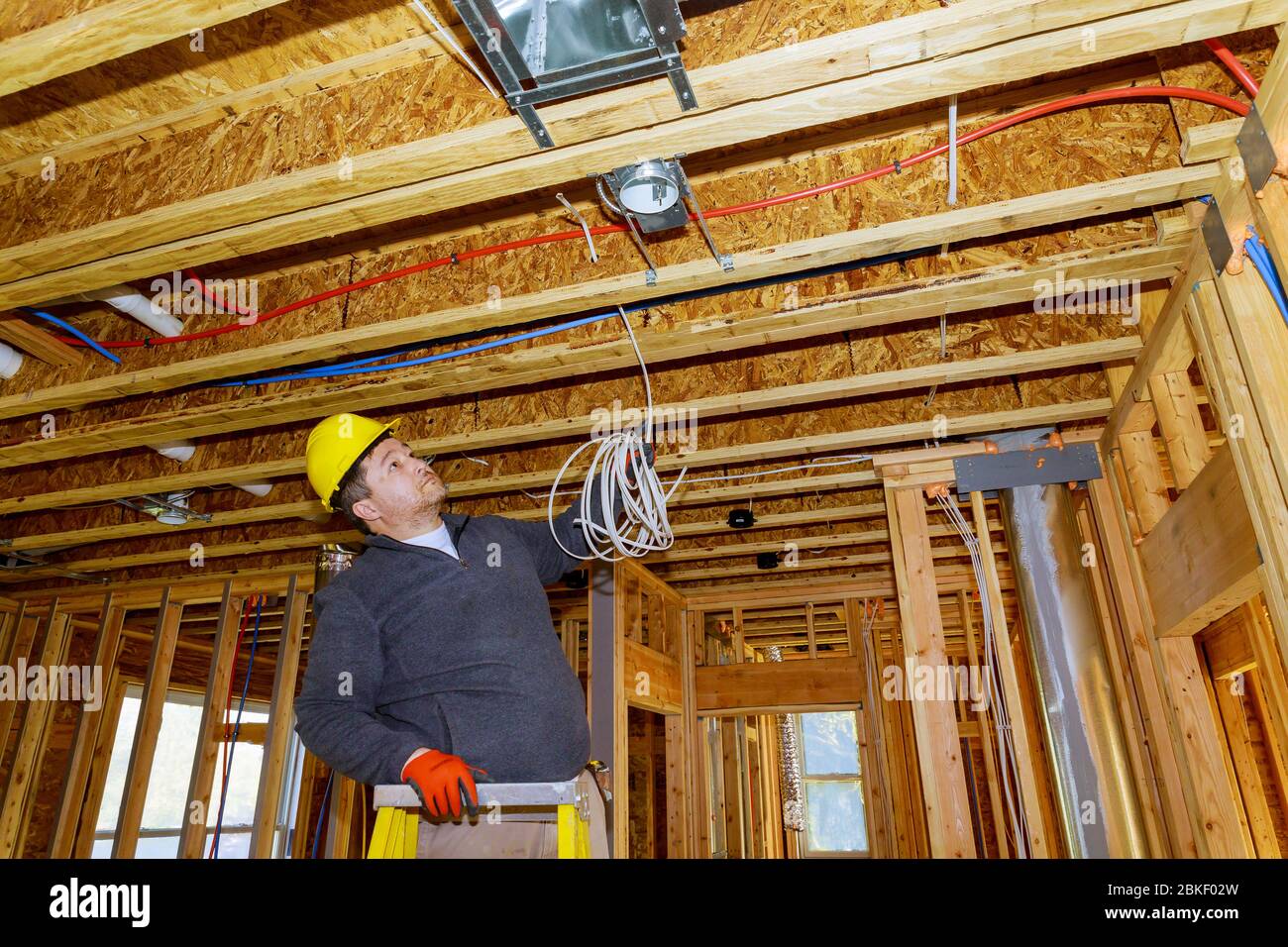 Electrician installing electrical cable wire in new house construction