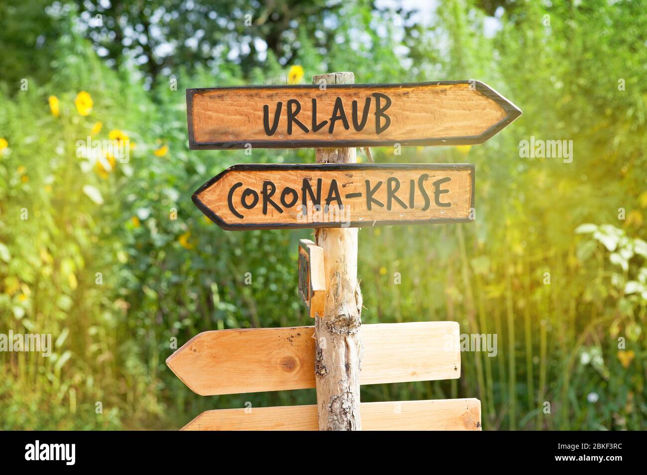 Wooden direction sign with the German words vacation and Corona crisis (Urlaub, Corona-Krise) Stock Photo