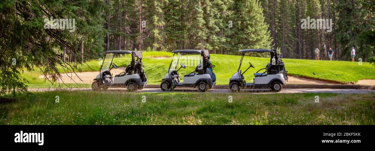 Row of empty electric carts on the side of the golf course, in Banff, Alberta, Canada Stock Photo
