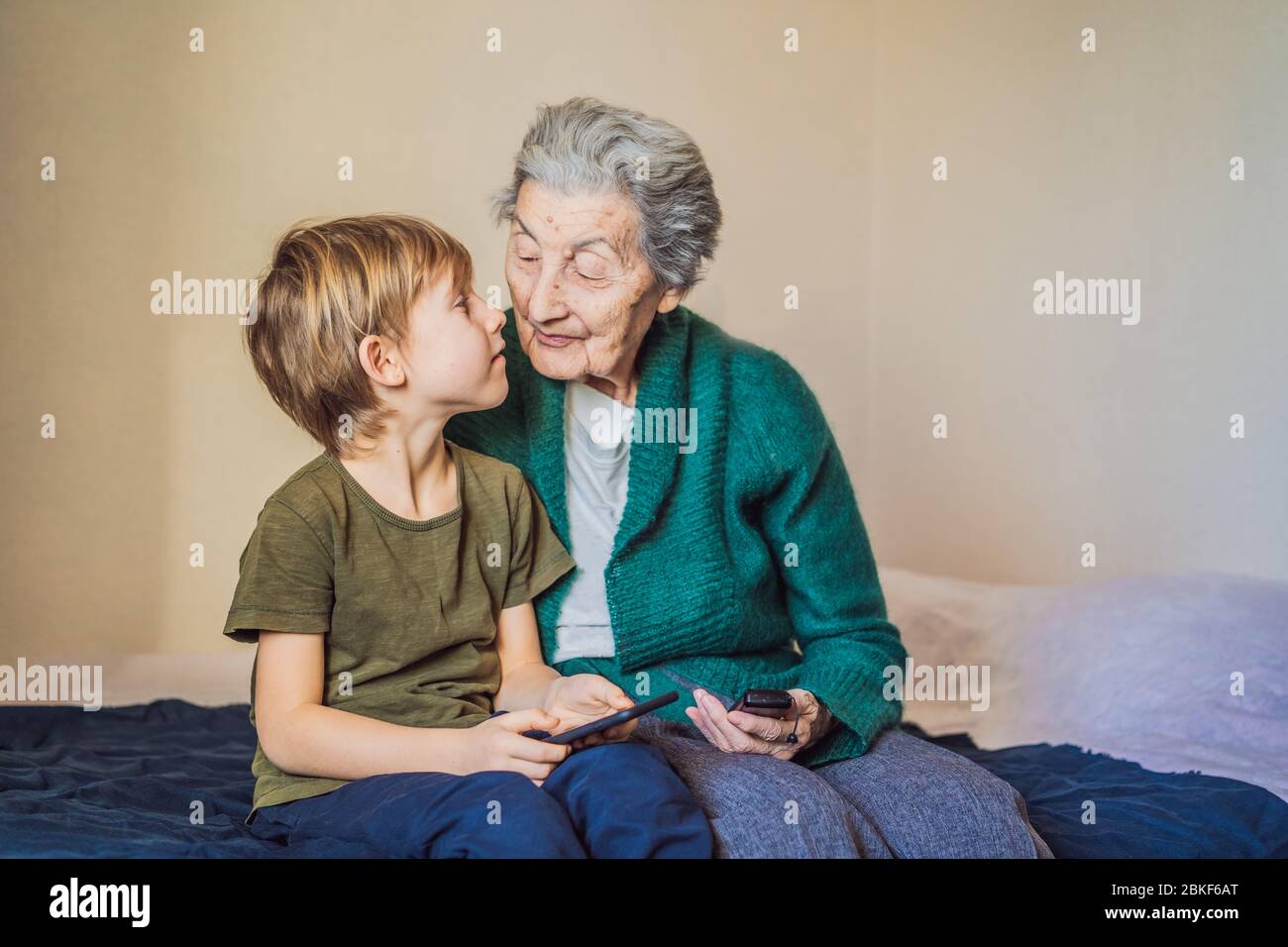 Coronavirus is over. Quarantine weakened. Take off the mask. Now you can meet with grandmother. Old woman and her grandson. Stock Photo