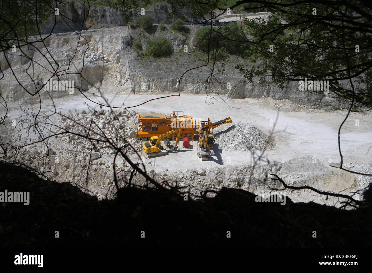 Overlooking a bright chalk quarry to the heavy machines that look like toys Stock Photo