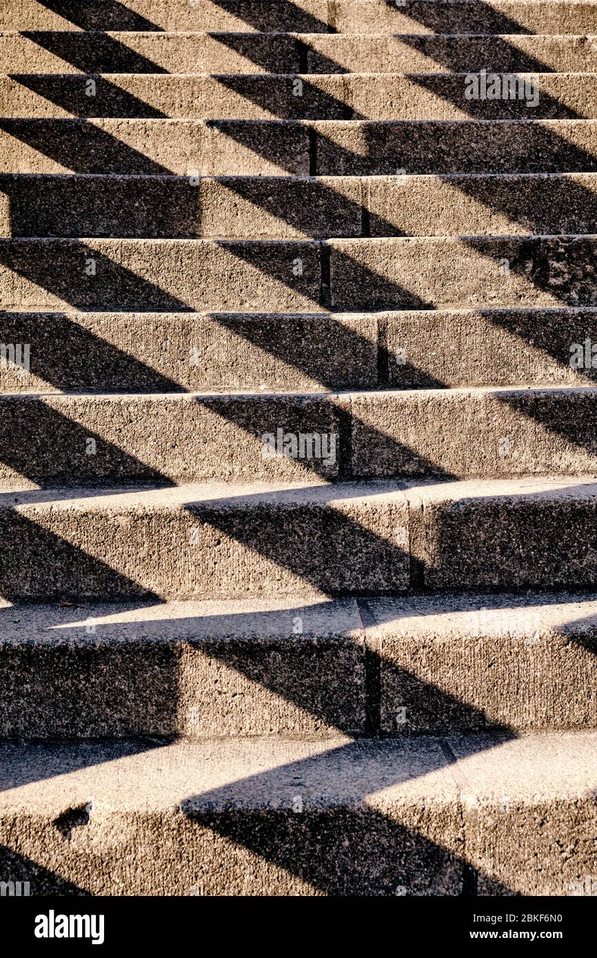 Abstract background shot with a pattern created by harsh shadows on a concrete staircase in the city. Seen in Germany in April. Stock Photo
