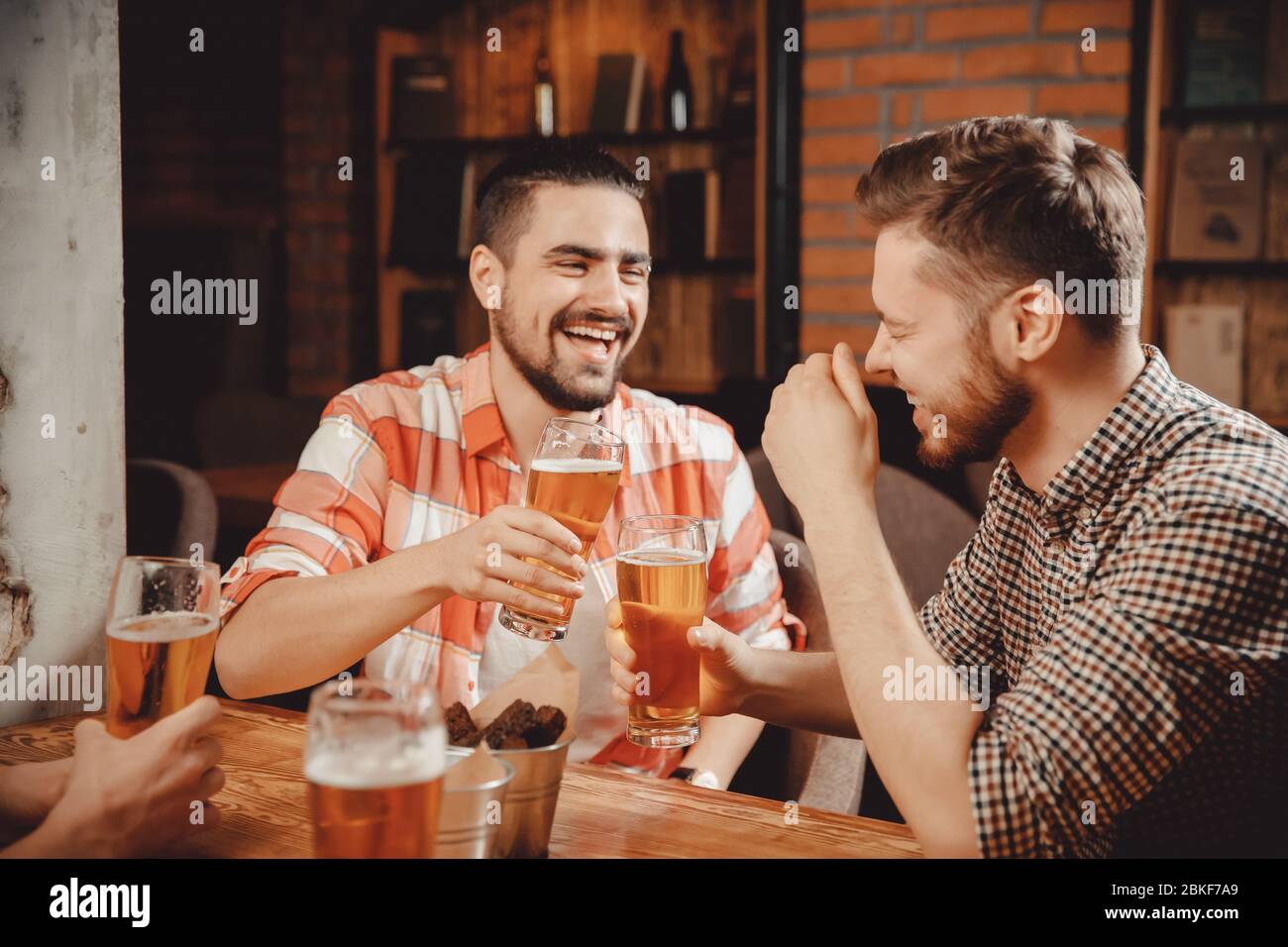 Two bearded young men plaid shirts relax bar, laugh, tell funny stories,  drink draught beer in pub, clanging glasses Stock Photo - Alamy
