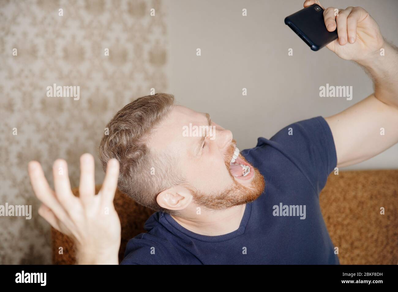 Man shouts holding phone. Loss concept loosing mobile games online. Stock Photo