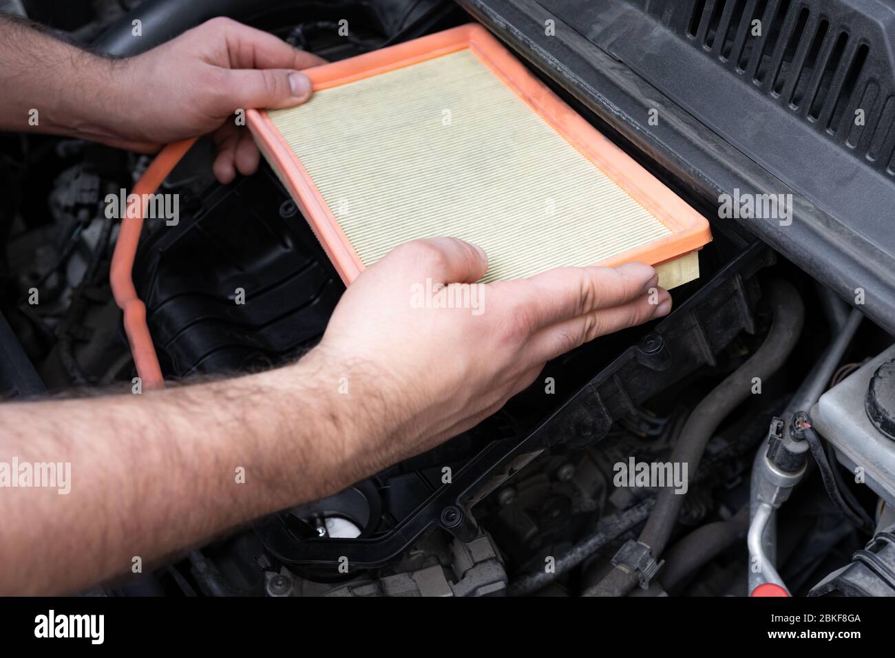 Caucasian man changing new air filter in car engine bay. Mechanic