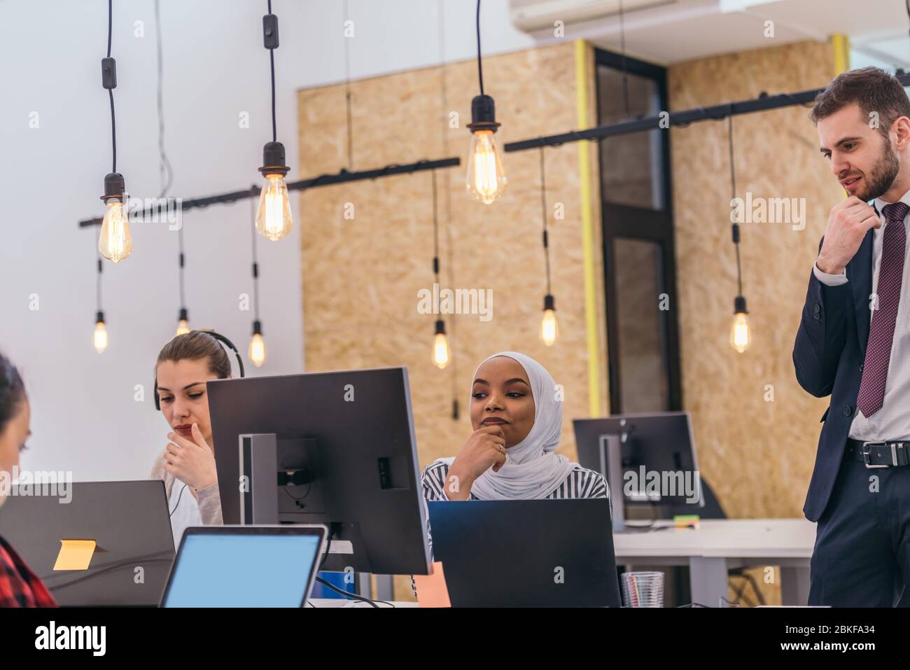 Handsome young executive explaining new employees an online task on theirs computers Stock Photo