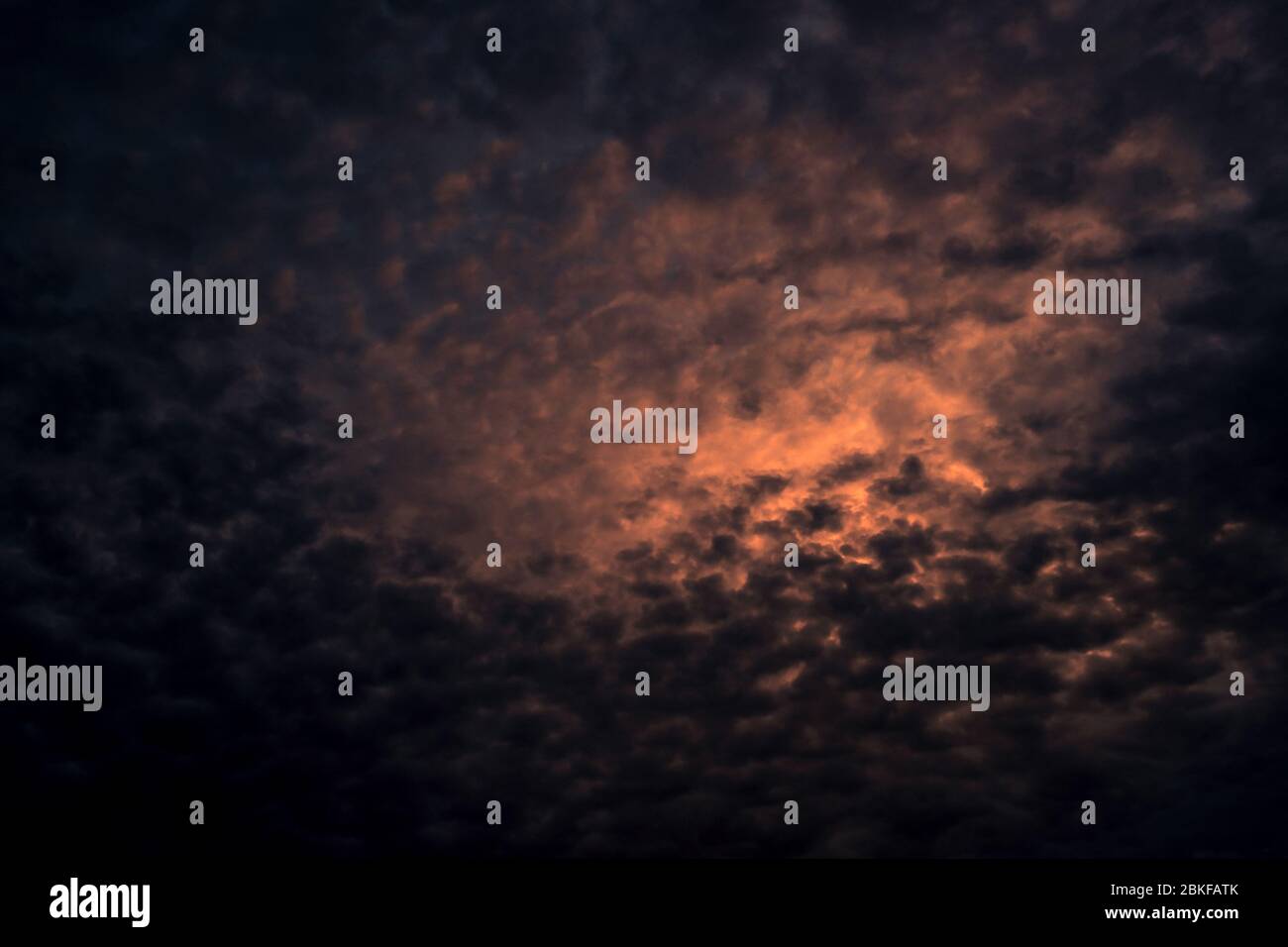 Red light of sun in dark cloudy sunset sky. Dramatic sky with beautiful pattern of fluffy clouds. Mental power or psychic power background. Power Stock Photo
