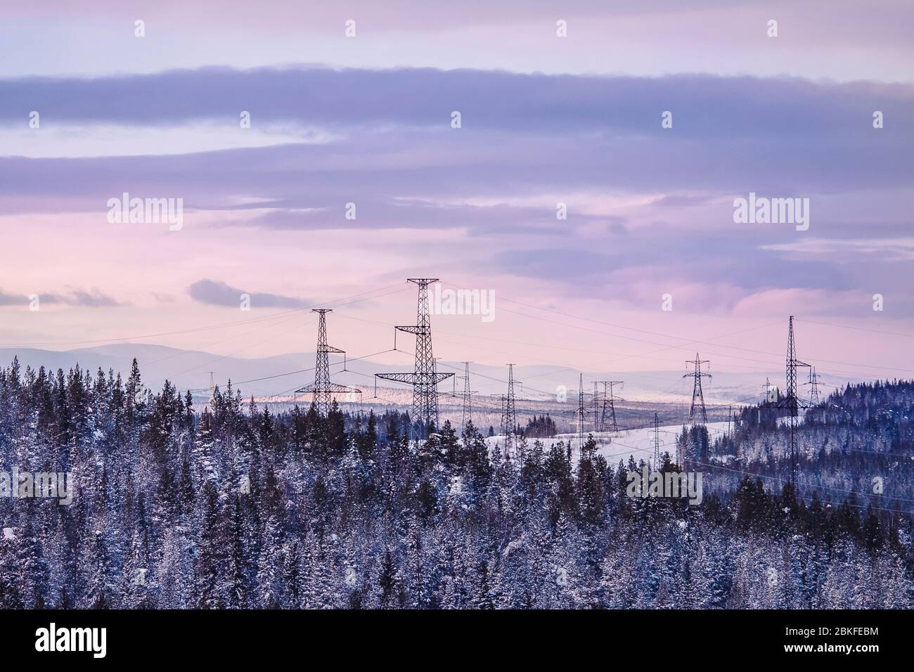 Against background of cloudy sky, Pillar power line electric towers are ...