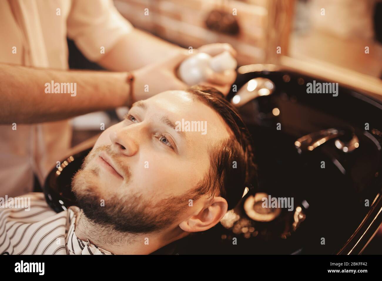 Close up Hairdresser man washing beard client head at Barber shop. Concept haircare Stock Photo
