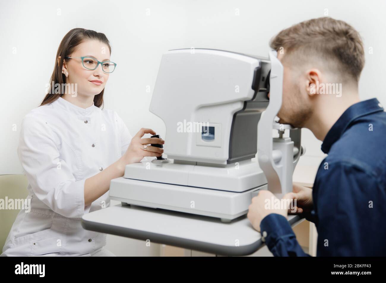 Female doctor ophthalmologist clinic checks eye vision of man on machine lamp. Concept
