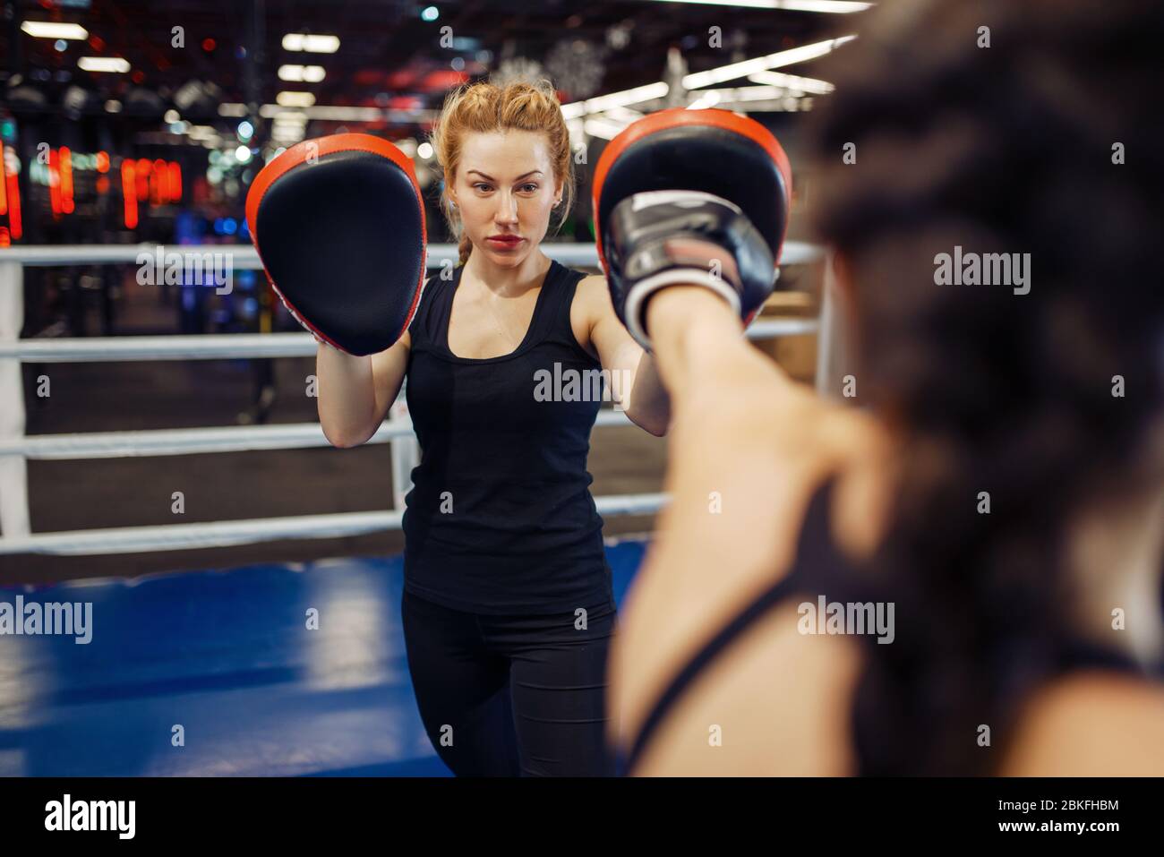 Woman in gloves boxing in the ring with trainer Stock Photo