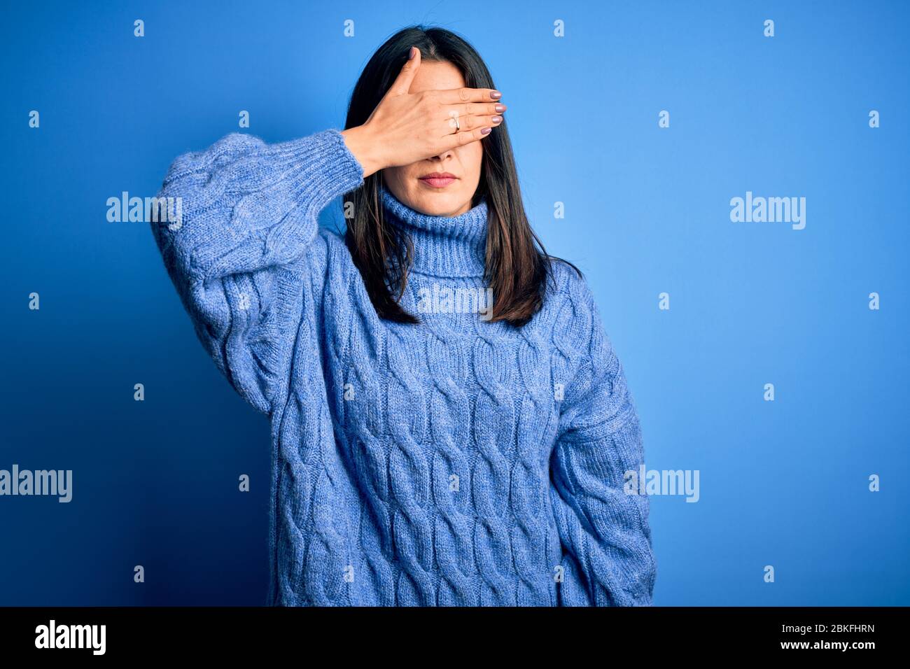 Young brunette woman with blue eyes wearing casual turtleneck sweater ...