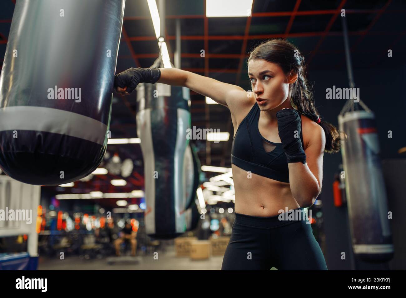 Woman in boxing bandages hits a punching bag, box Stock Photo
