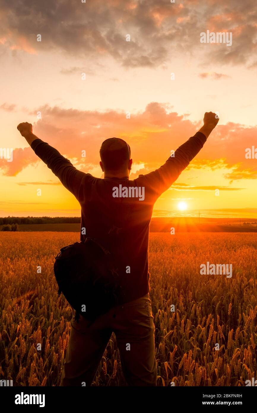 Silhouette of a man raise his hands up to sunset on the field with ...