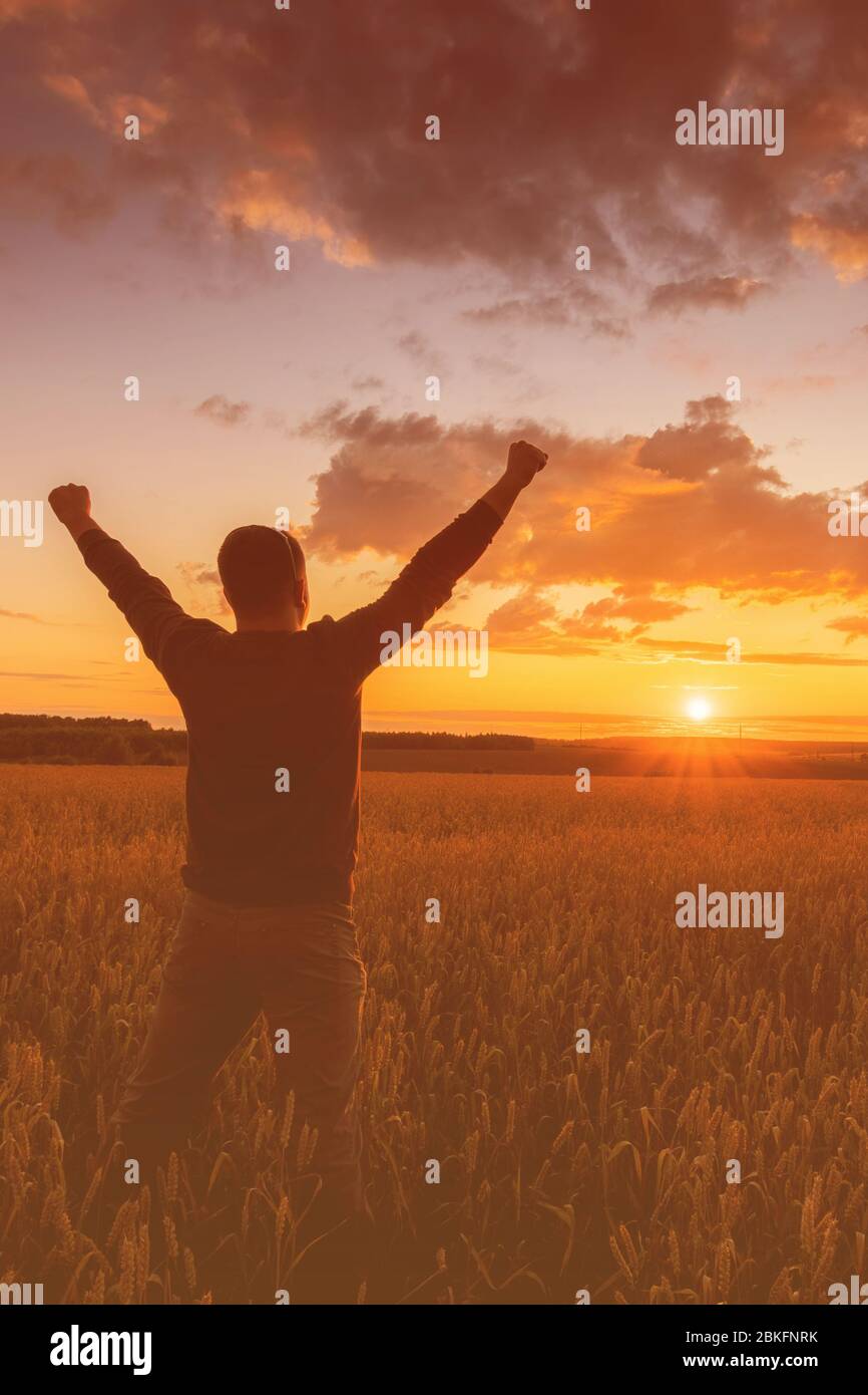 Silhouette of a man raise his hands up to sunset on the field with ...