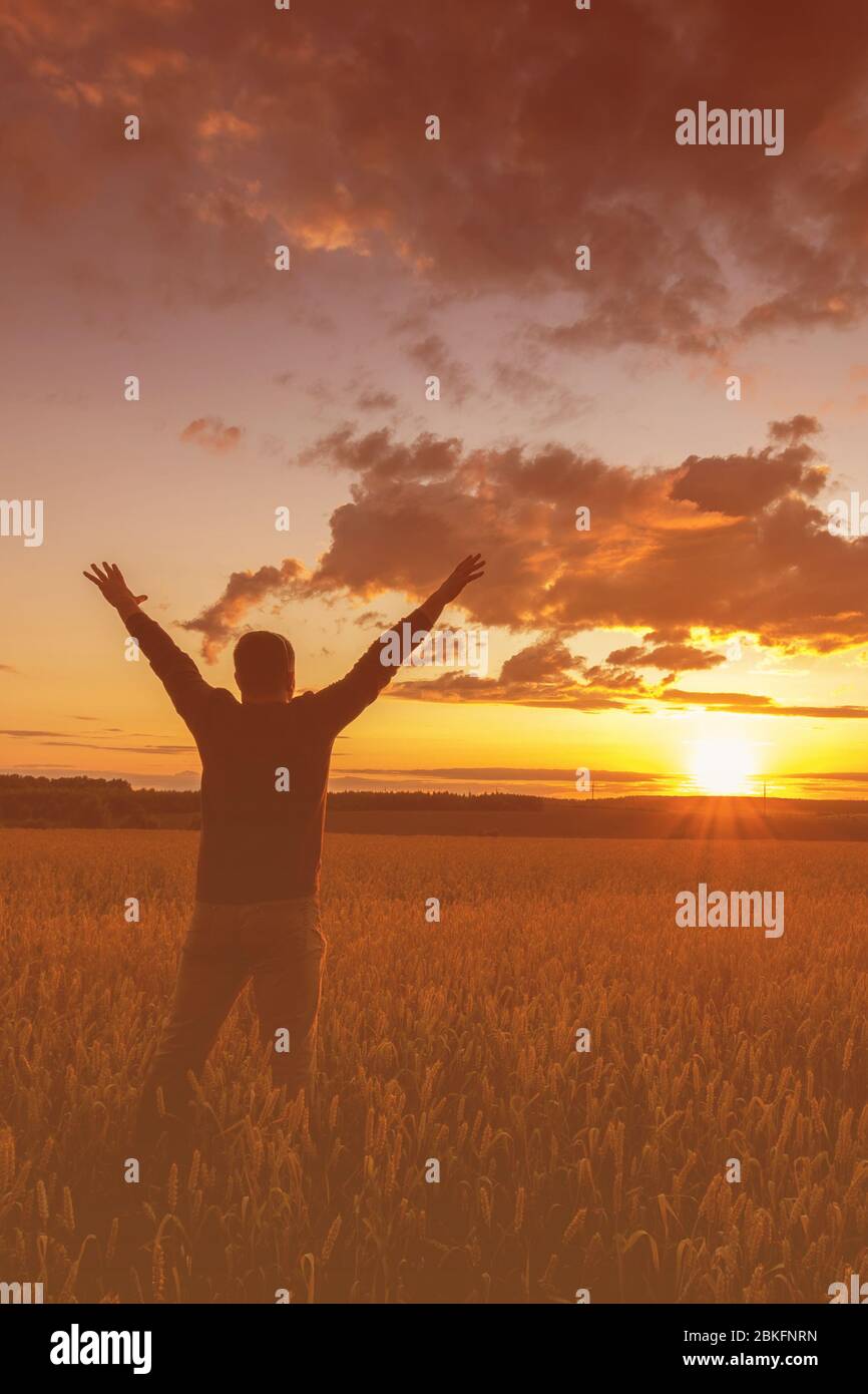 Silhouette of a man raise his hands up to sunset on the field with ...