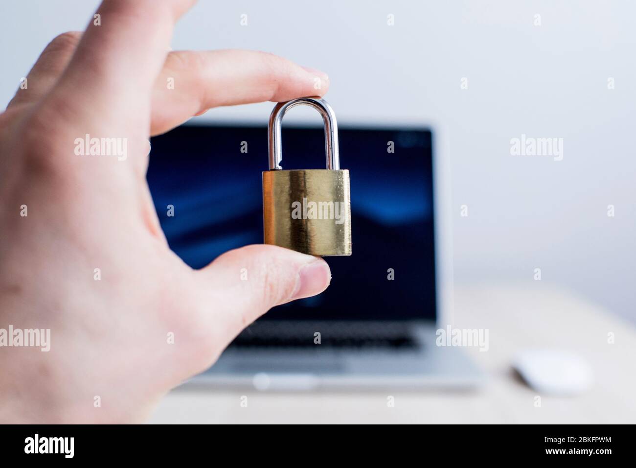 A male hand is locking an unlocked padlock in front of a blurry