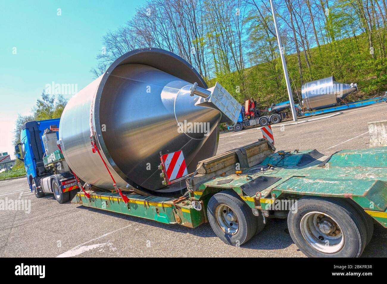 AACHEN, NRW, GERMANY, April 18, 2019: Heavy haulage of a big stainless steel container on a special low-loader trailer truck, parking road sight Stock Photo